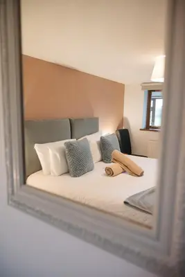 a mirror reflecting a bed with pillows on it at Vale Farm Cottages in Brecon