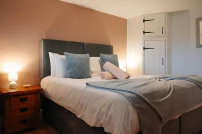 a bedroom with a large bed with blue and white pillows at Vale Farm Cottages in Brecon