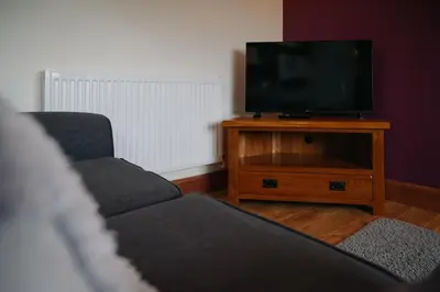 a living room with two couches and a flat screen tv at Vale Farm Cottages in Brecon