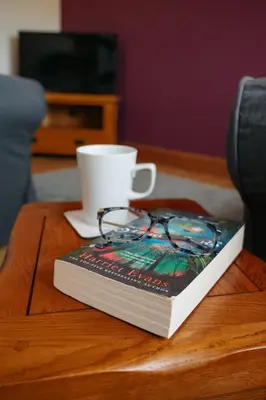 a book and a cup on a table with a coffee mug at Vale Farm Cottages in Brecon