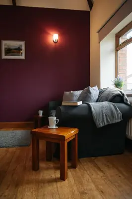 a living room with a black couch and a table at Vale Farm Cottages in Brecon