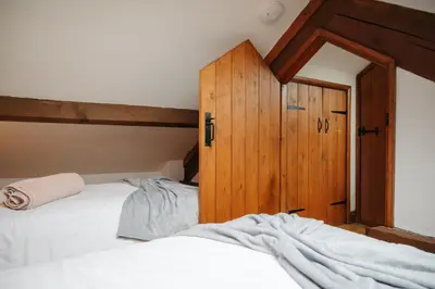 a bedroom with two beds and a wooden cabinet at Vale Farm Cottages in Brecon