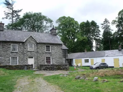 an old stone house with a car parked in front at cosy ground floor disabled friendly room in farm house in Bala