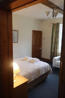 a bedroom with a bed and a table and a window at cosy ground floor disabled friendly room in farm house in Bala