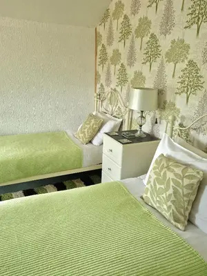 a bedroom with two beds and a lamp on a table at Ty Llew in Llandysilio