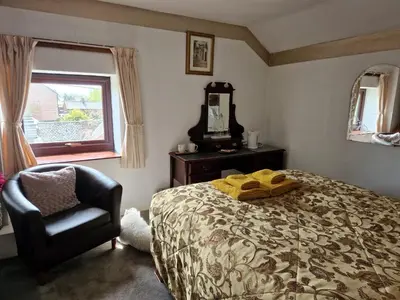 a bedroom with a bed and a chair and a mirror at Ty Llew in Llandysilio