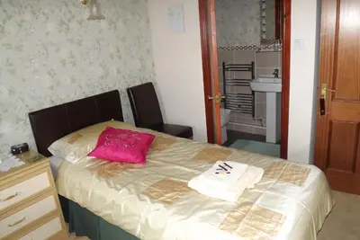 a bedroom with a bed with a pink pillow on it at Hillcrest Guest House in Llangollen
