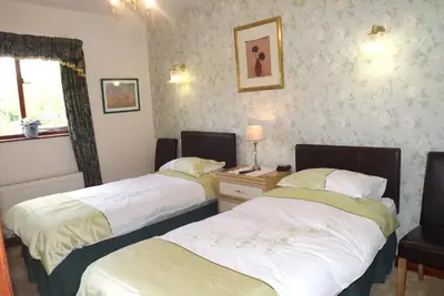 a bedroom with two beds and a desk with a lamp at Hillcrest Guest House in Llangollen