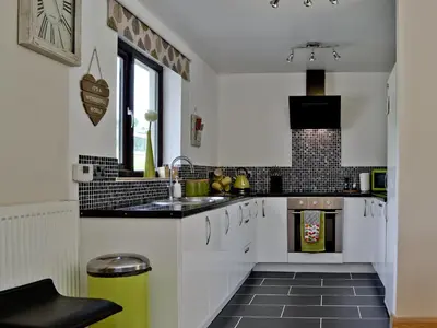 a kitchen with white cabinets and a sink at River Cottage in Llangunllo