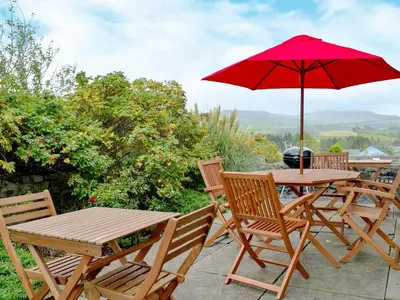 a table and chairs with a red umbrella at Yr Hen Fanc in Trawsfynydd