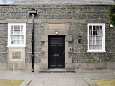a stone building with a black door and two windows at Yr Hen Fanc in Trawsfynydd