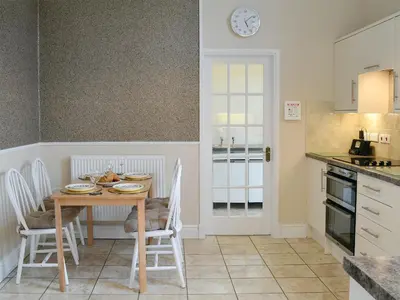 a kitchen with a table with chairs and a clock on the wall at Yr Hen Fanc in Trawsfynydd