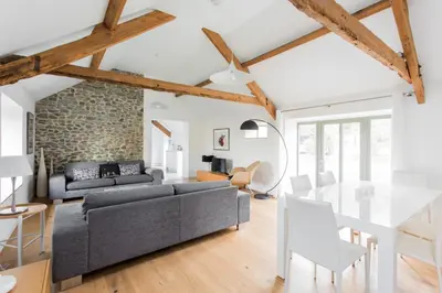 a living room with a gray couch and a stone wall at Owl Barn at Penygaer Great views of Brecon Beacons in Llandovery