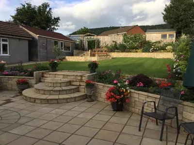 a garden with a retaining wall and a patio at Carinya in Talgarth