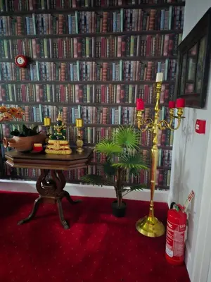 a room with a wall of books with a table and a lamp at Bluebells guest house in Barmouth