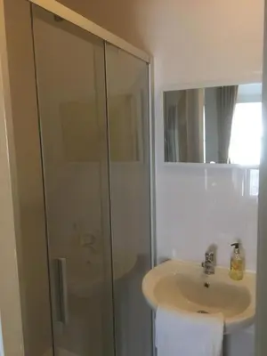 a white bathroom with a sink and a shower at Bluebells guest house in Barmouth