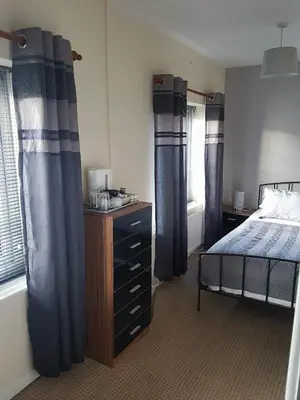 a bedroom with blue curtains and a bed and a dresser at The Lamb and Flag Inn in Rhayader