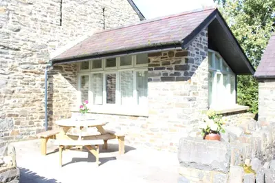 a picnic table in front of a stone cottage at Granary Cottage with hot tub on organic farmland in Lampeter