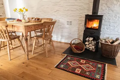 a living room with a table and a wood stove at Granary Cottage with hot tub on organic farmland in Lampeter