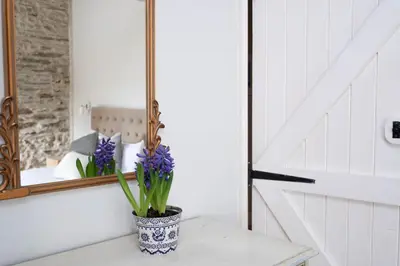 a vase of purple flowers on a table in front of a mirror at Granary Cottage with hot tub on organic farmland in Lampeter
