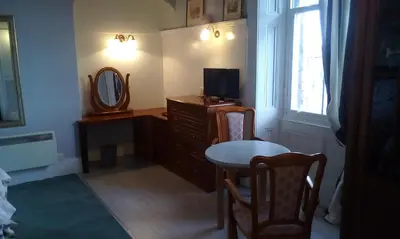 a room with a dresser and a mirror and a table at Tower Hotel in Talgarth