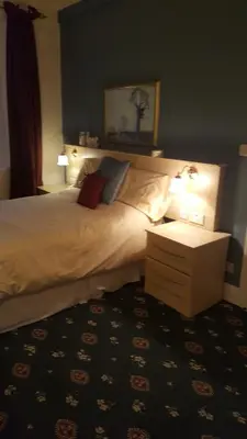a bedroom with a bed with two lamps and a table at Tower Hotel in Talgarth
