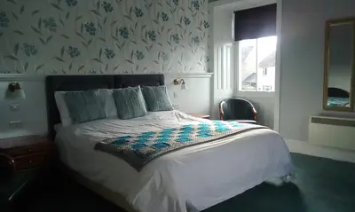 a bedroom with a white bed with a blue and white blanket at Tower Hotel in Talgarth