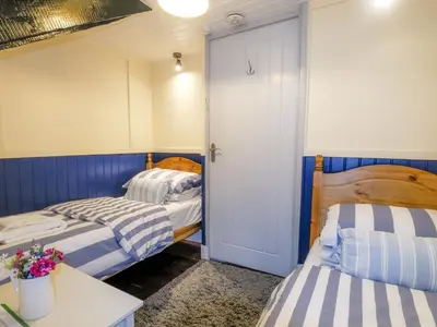 two beds in a room with blue and white stripes at Y Bwthyn in Tal-gareg