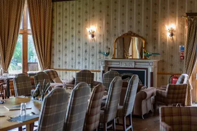 a room with tables and chairs and a fireplace at Mellington Hall Country House Hotel in Church Stoke