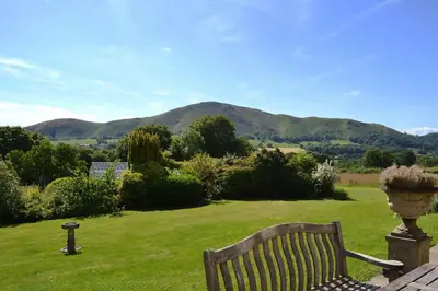 a bench in a field with mountains in the background at The Oaks in Church Stretton