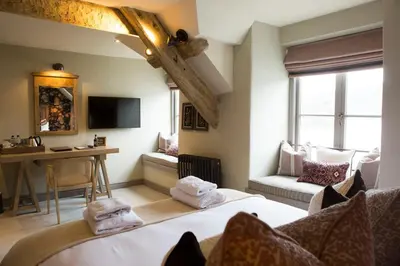a room with a bed and a desk and a television at George III Hotel in Penmaenpool