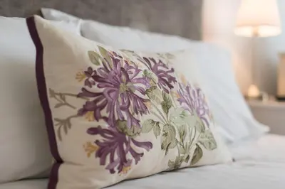 a pillow with a flower pattern on it sitting on a bed at Marine Studios in Aberystwyth