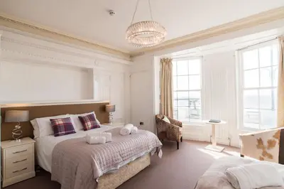a bedroom with a large bed and a chandelier at Marine Studios in Aberystwyth