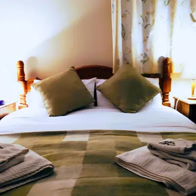 a bed with two pillows and two towels on it at Pwllgwilym B & B in Builth Wells