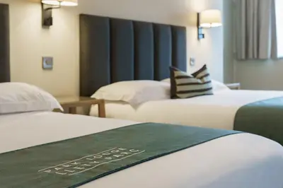 two beds in a hotel room with a green sign on them at Aberystwyth Park Lodge Hotel in Aberystwyth