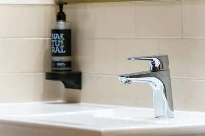 a bathroom sink with a faucet and a bottle of soap at Aberystwyth Park Lodge Hotel in Aberystwyth