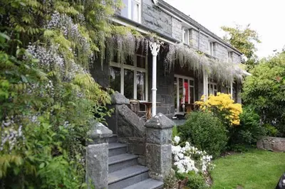 a stone house with a red door and some flowers at Ty Mawr Hotel in Llanbedr
