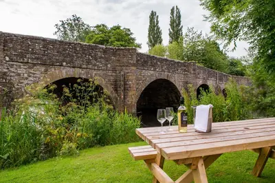 a wooden picnic table with wine glasses and a bottle at The Lion in Leintwardine