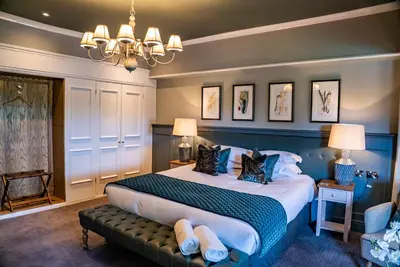 a bedroom with a large bed and a chandelier at Mytton and Mermaid - Brunning and Price in Shrewsbury