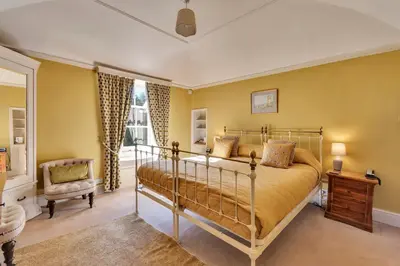 a bedroom with a bed and a chair and a window at Tyddyn Llan Restaurant with Rooms in Corwen