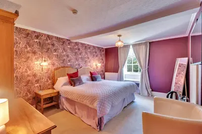 a bedroom with a bed and a purple wall at Tyddyn Llan Restaurant with Rooms in Corwen