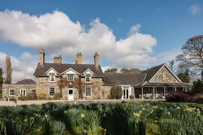 a large stone house with a garden in front of it at Tyddyn Llan Restaurant with Rooms in Corwen