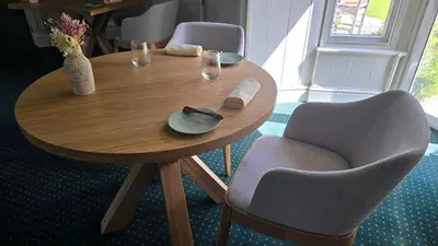 a wooden table with two chairs and a table with glasses at Tyddyn Llan Restaurant with Rooms in Corwen