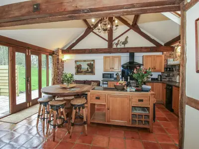 an open kitchen with a table and stools at Corn House in Plaish