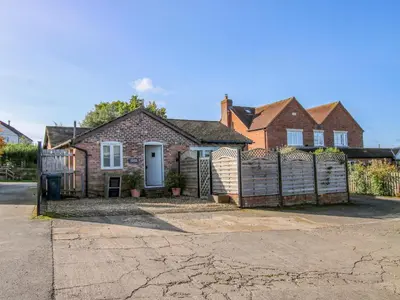 a brick house with a fence in front of it at Virginia Cottage in Acton Burnell