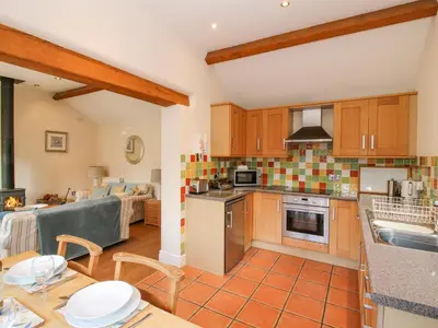 a kitchen and living room with a table and chairs at Virginia Cottage in Acton Burnell