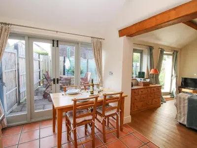 a dining room with a table and chairs and a balcony at Virginia Cottage in Acton Burnell