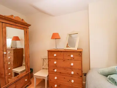 a bedroom with a dresser and a mirror at Virginia Cottage in Acton Burnell