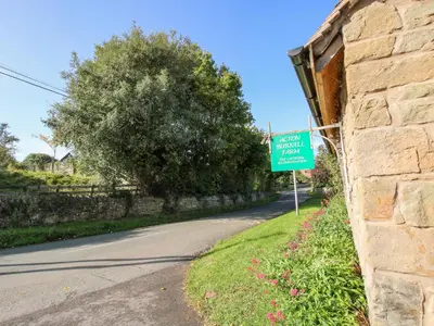 a green sign on the side of a road at Virginia Cottage in Acton Burnell