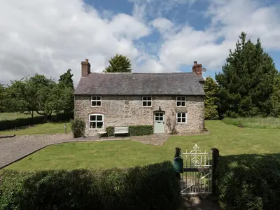 an old stone house with a gate in front of it at Hillgate House in Bromlow